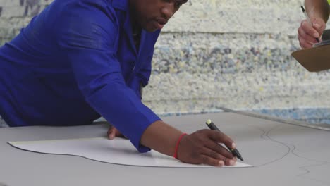 Worker-drawing-a-pattern-on-a-cardboard