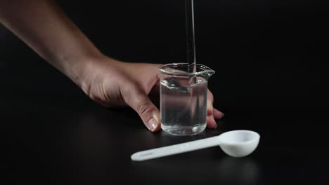 hand stirring salt in a beaker of water