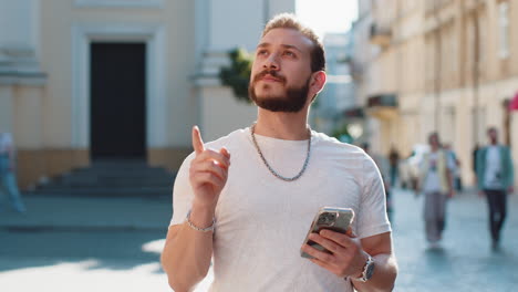 tourist traveler man guy using looking smartphone search a way on map in mobile navigator app