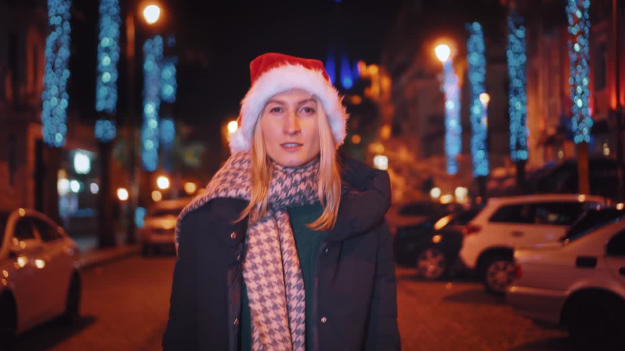 산타클로스 모자를 입은 아름다운 여성이 크리스마스 밤에 고 있습니다.