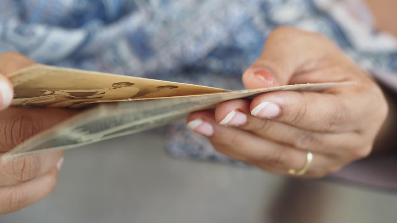 Woman holding and examining old, possibly damaged photos