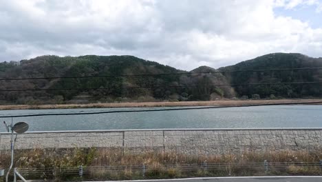 passing by a tranquil lake and hills while driving