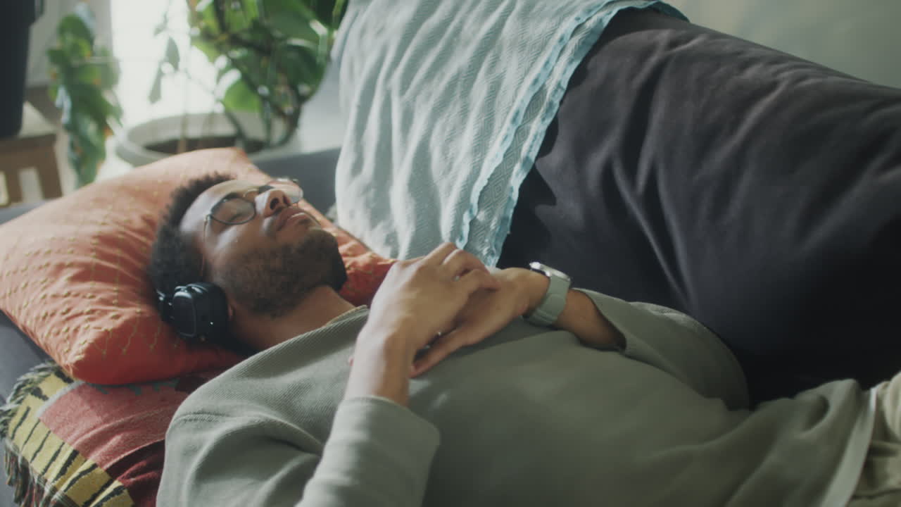 Uomo che ascolta musica con le cuffie sul divano