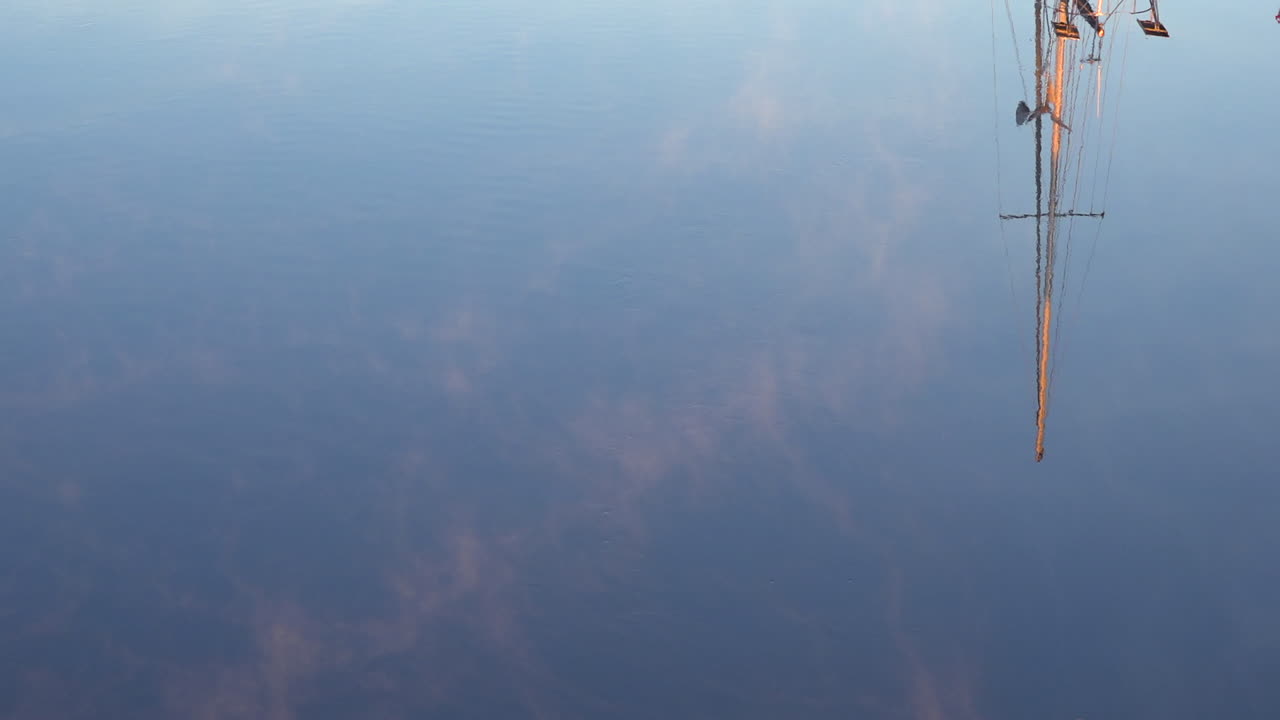 이 예술적인 장면에서 돛대가 항구의 물에 반사됩니다.