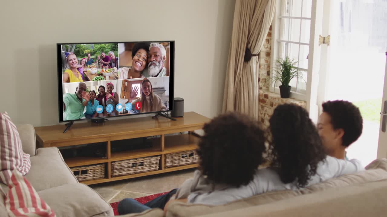 Famiglia afroamericana che fa una videochiamata in TV mentre è seduta sul divano a casa