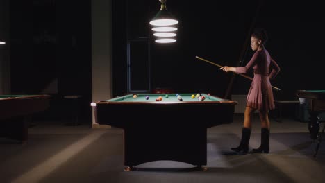 mujer jugando al billar en una habitación oscura