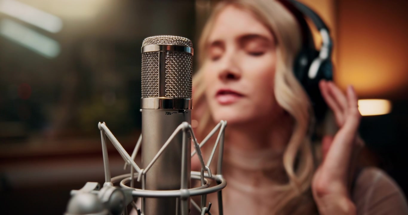 Giovane donna che canta in un microfono professionale in uno studio di registrazione