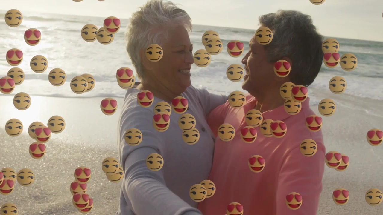 Un couple de personnes âgées se tenant la main, dansant sur la plage, une cascade d'émojis défile depuis la gauche pour le marketing