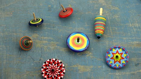 various colorful whirligigs top spins collection on old blue wooden table background