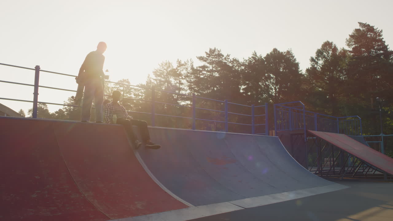 Guys Resting on Ramp in Skatepark in Evening