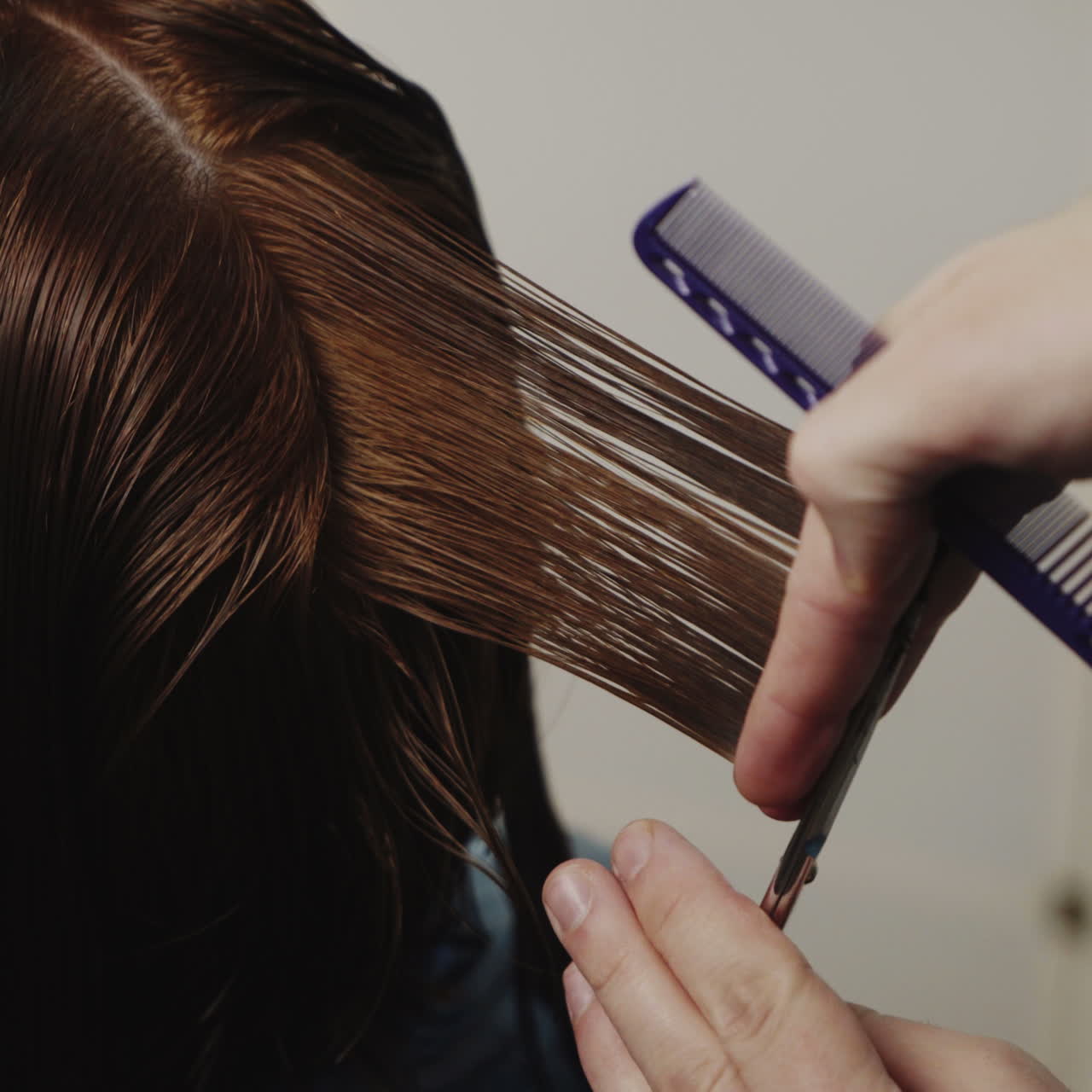 Young male hairdresser working. Trimming brown hair with scissors. Close-up Square video