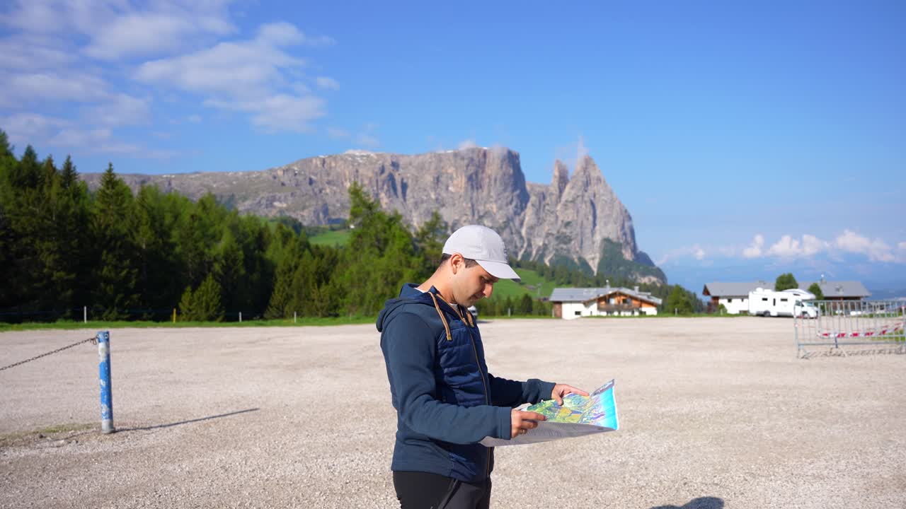 hombre aventurero navegando con un mapa topográfico desde el estacionamiento de alpe di siusi, italia