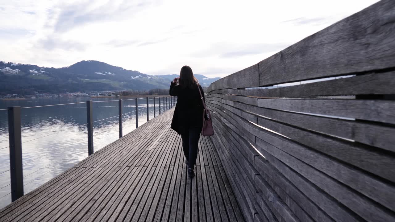 siguiente toma de una joven asiática caminando en un muelle de madera en rapperswil, suiza en cámara lenta