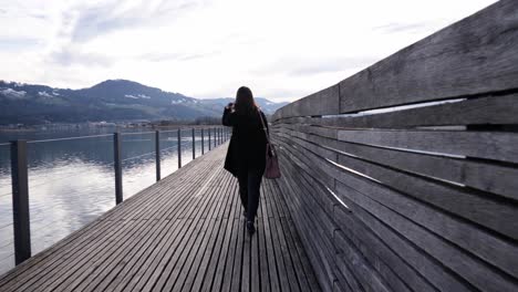 following shot of a young asian woman walking on a wooden pier in rapperswil, switzerland in slow motion