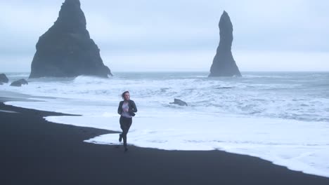 gloomy icelandic beach landscape with woman running. aerial flying backwards