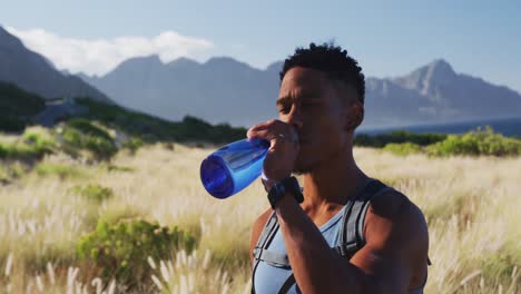 african american man cross country running drinking water in mountain countryside