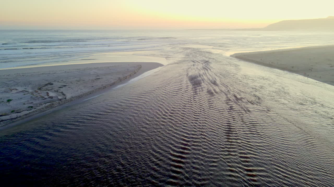 Lagoon breached sandbar to run into ocean at sunset