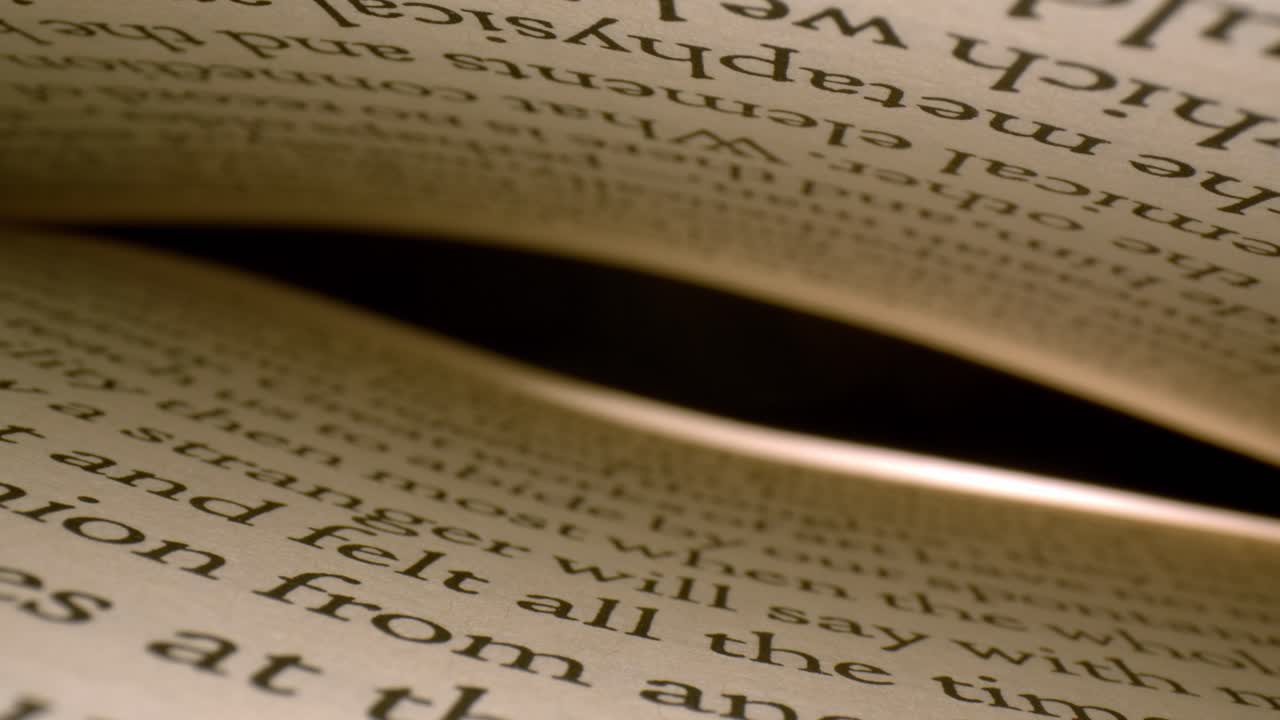 Enveloped by pages of a book, top page curves towards the bottom, pausing and then moving very quickly through the pages into the interior of book