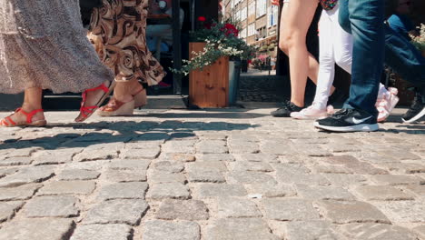 People-walk-on-a-crowded-sidewalk,-close-up-view-of-the-sidewalk-and-legs-to-knee-height,-slow-motion-on-shoes-and-footsteps