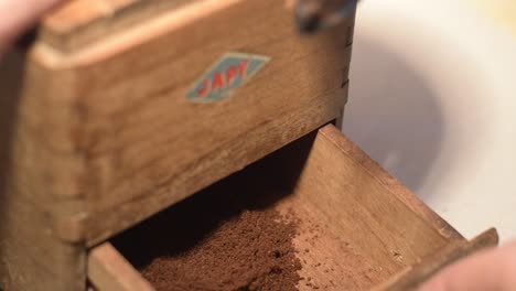 man opens an old coffee grinder with ground coffee japy grinder