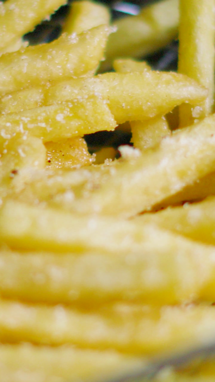 Vertical Video Close Up of Crispy French Fries in Fryer Basket After Cooking in Hot Oil. Unhealthy Tasty Fast Food.