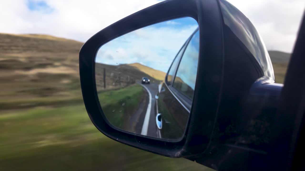 Specchietto retrovisore dell'auto che mostra il veicolo che segue su una strada tortuosa con effetto mosso