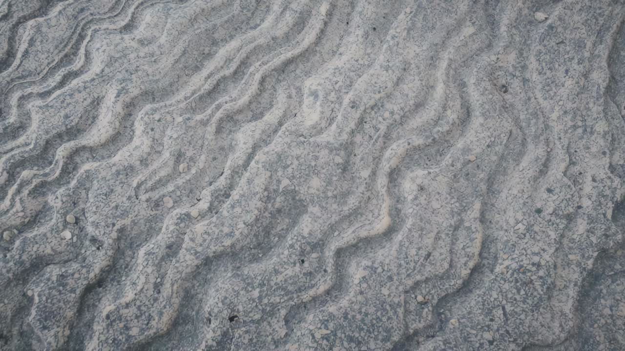 Drifting camera framing near rippled sediment surface, capturing textures with pebbles for analysis