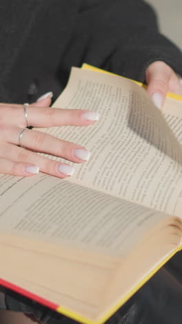 primer plano de las páginas del libro siendo giradas por una dama con uñas bien cuidadas adornadas con un anillo, mostrando la acción de la lectura en un día soleado con un efecto de fondo borroso suave