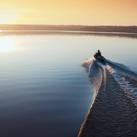 boat on water surface at sunset. people driving the motor boat quickly along the evening river on beautiful water background. aerial view.