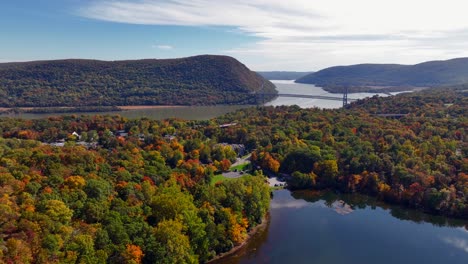 an aerial view over a reflective lake with colorful trees in autumn, upstate ny