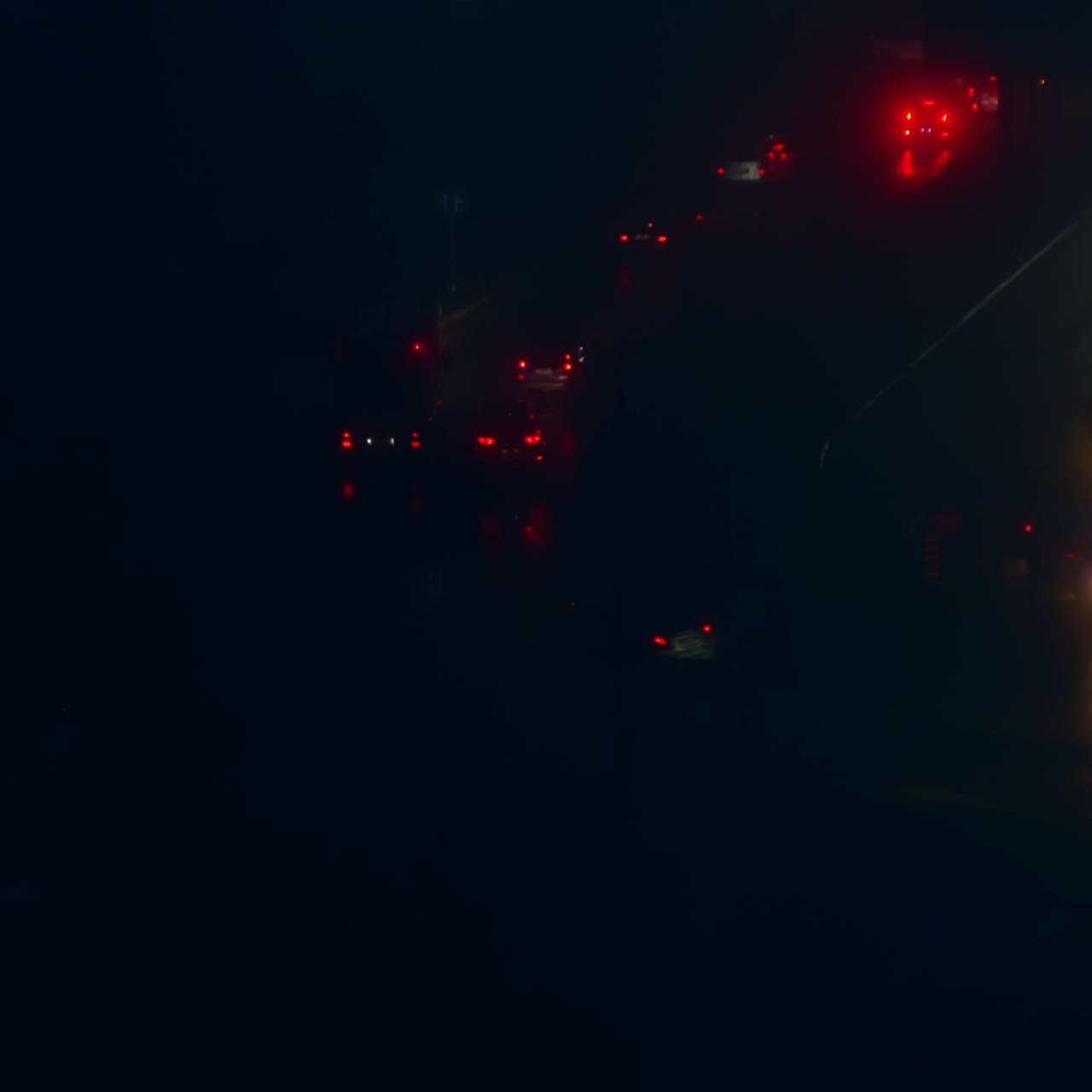 Two-way road with cars moving slowly along. Dark street with only headlights from vehicles in time of blackout