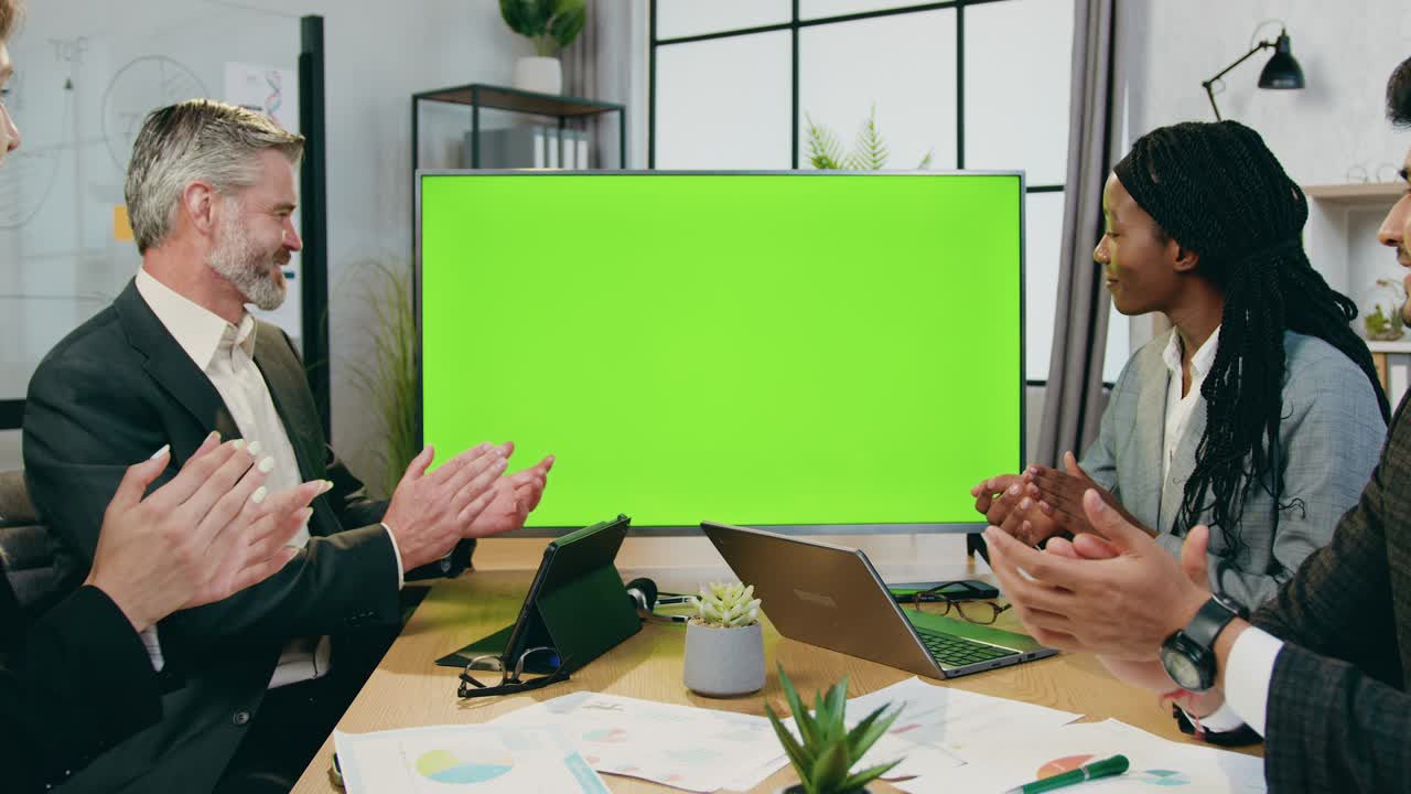agradable positivo confiado cualificado equipo de negocios diverso sentado en la oficina de la compañía anuncio aplaudiendo las manos antes o después de una presentación exitosa en la televisión con croma verde, concepto de tecnología moderna