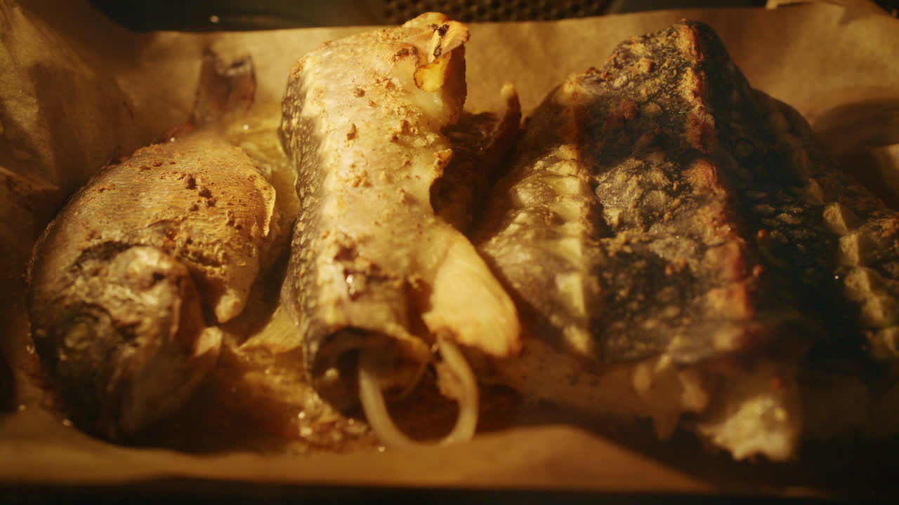Fresh fish pieces roasting in the oven on a tray, golden surface and steam visible