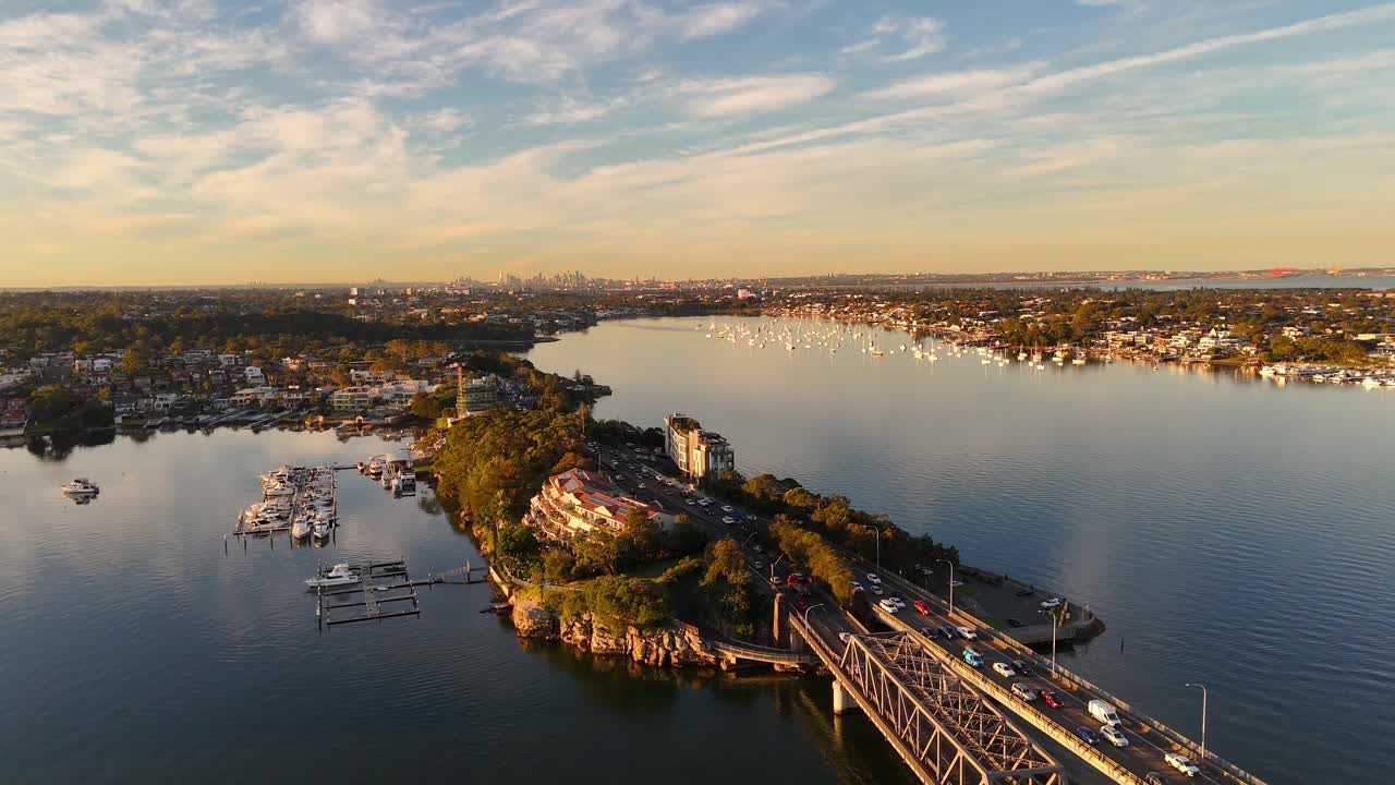 Establishing drone of Blakehurst suburb highway bridge with calm waters and golden sunset light, Sydney NSW Australia