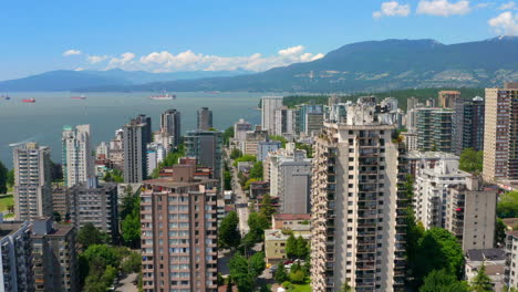 stanley park revealed behind high-rise condominium buildings in west end peninsula at the coast of burrard inlet in vancouver, bc, canada