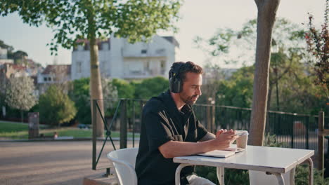 inspired man enjoying music at wireless earphones sitting city street close up