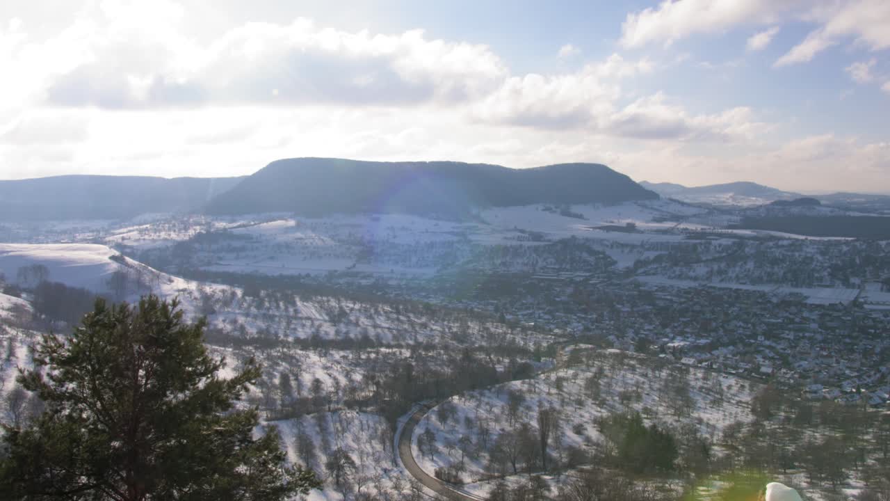 독일 스와비아의 멋진 풍경 위에 산과 태양이 카메라에 반사되는 겨울 원더랜드를 가로질러 오른쪽에서 왼쪽으로 패닝