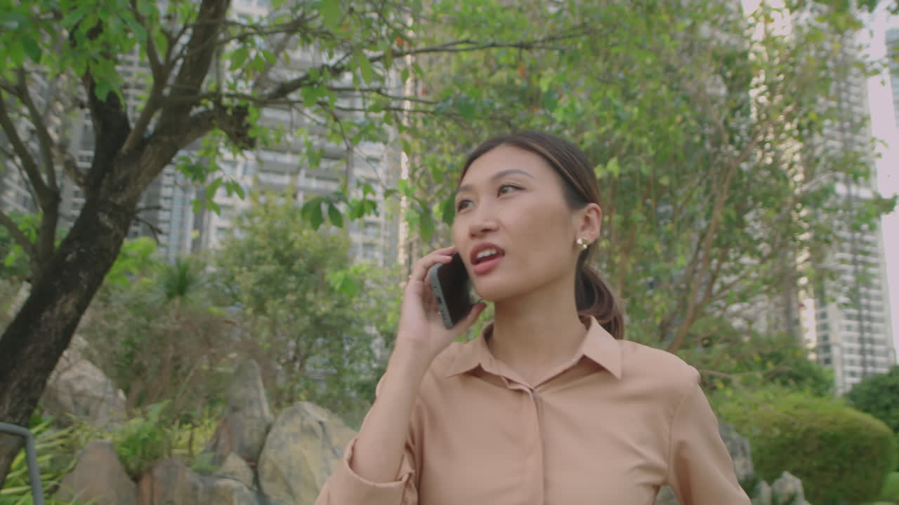 Asian Woman Having Phone Talk while Walking Outdoors