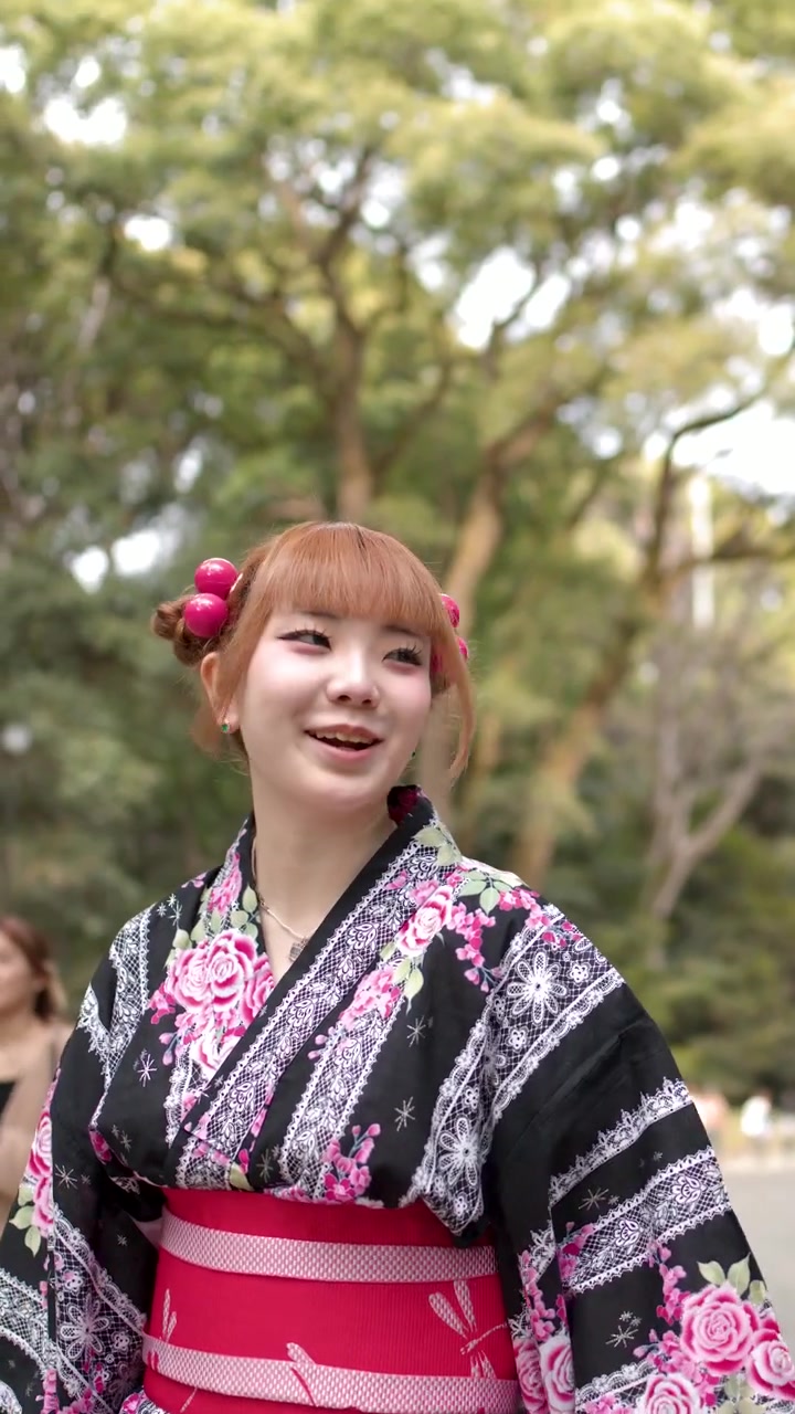 東京の神社で、伝統的な浴衣姿の女性2人が屋外を散策し、会話している様子。