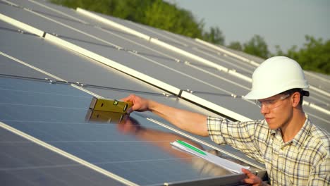 young enginneer installing new sunny batteries. worker in a uniform and hardhat installing photovoltaic panels on a solar farm. photovoltaic panel