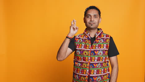 portrait of man crossing fingers and doing victory sign, studio background