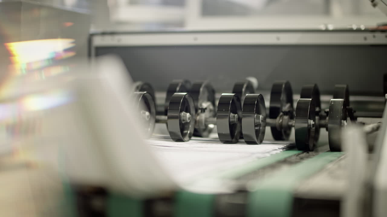 Produstion line in printing house, paper slowly beeing printed and moved with small wheels