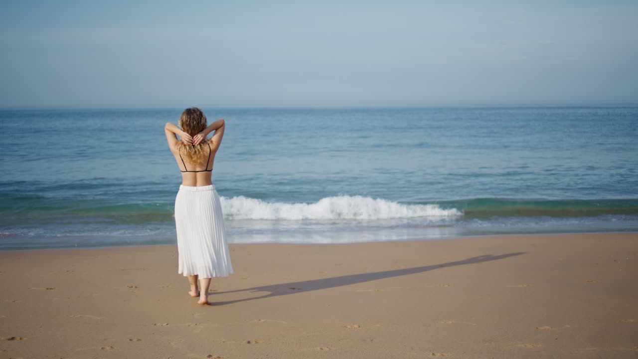바가에서 걸어다니는 여인 여행자 바다의 파도를 바라보며 뒤로 돌아다니는 소녀