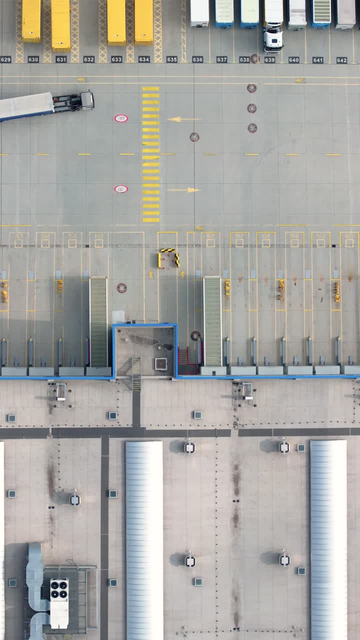 Aerial view of a freight terminal with unloading docks and parked trucks. Vertical video