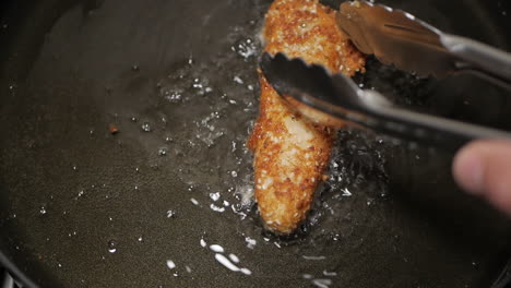 crumbed breast chicken fried in peanut oil in a pan