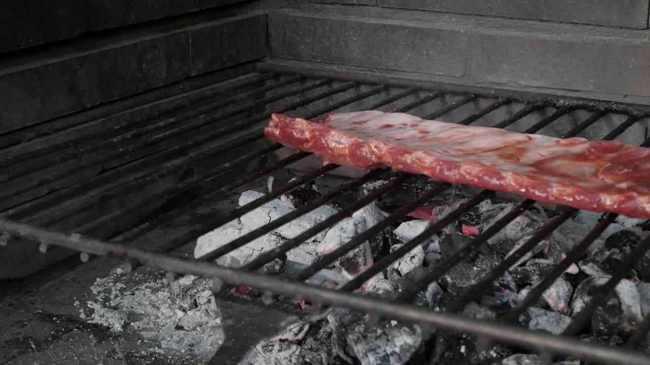 Juicy marinated rack of ribs cooking over hot coals on a barbecue grill