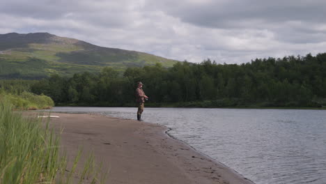 stylish fisherman throwing fishline into swedish river, side view