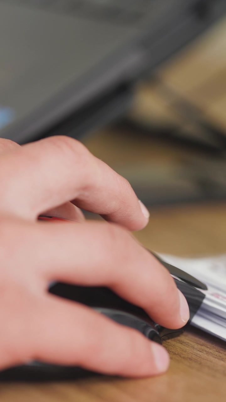 Primo piano che mostra una mano che clicca e muove un mouse del computer su una superficie di legno