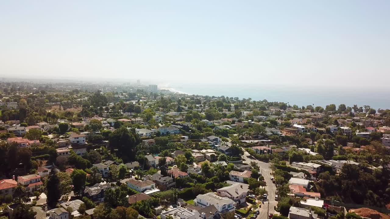 Aerial establishing shot of quaint american neighborhood with upper class houses and villas in California. Sunny autumn day with ocean in background. Los Angeles, Pacific Palicades, USA. Wide shot.