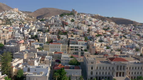 Aerial:-Slow-panoramic-drone-shot-of-Ermoupoli-city-in-Syros-island,-Greece-during-sunrise